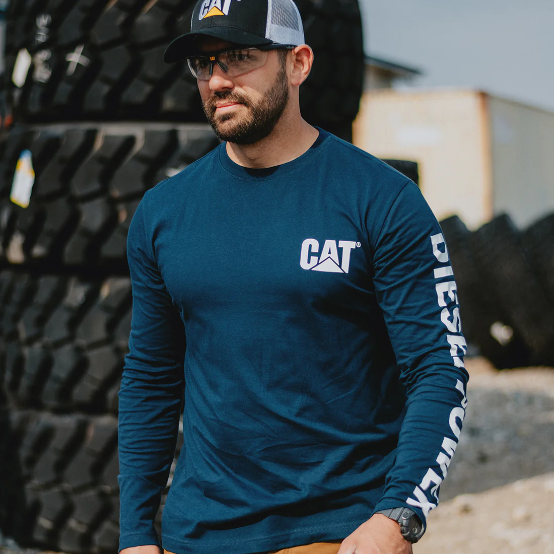 Lifestyle image of CAT Diesel Power Long Sleeve T-Shirt in blue worn by a man outdoors